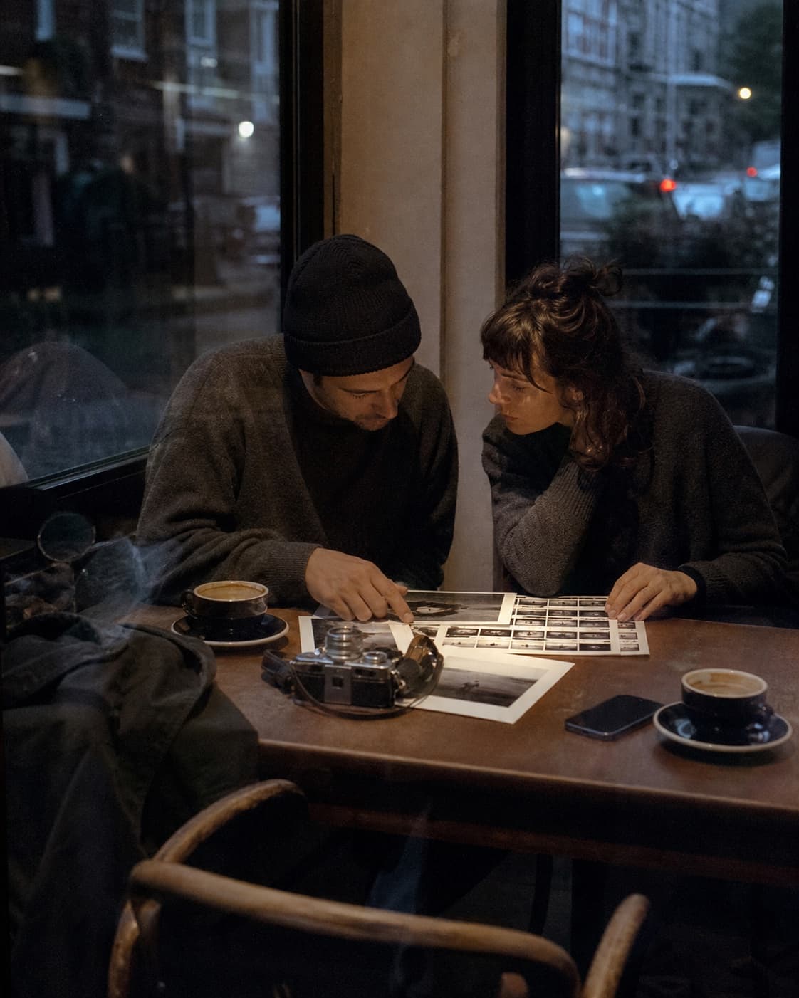 Two photographers reviewing prints beside a Leica camera